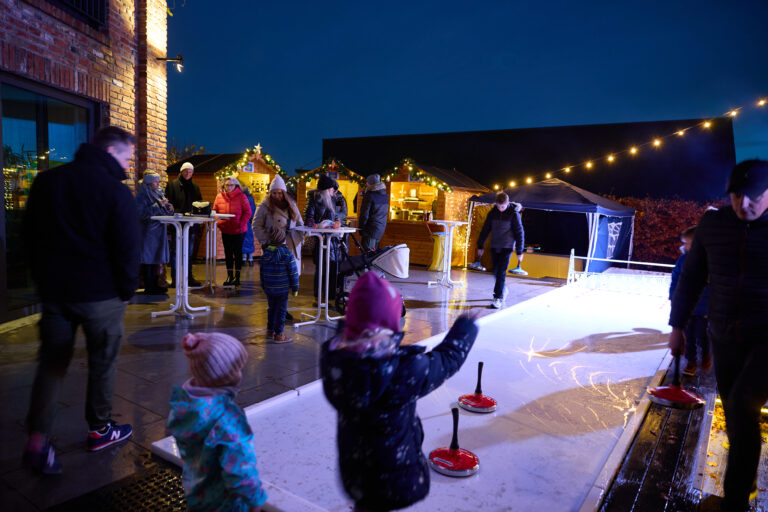 Eisstockbahn vor Weihnachtsbuden eines Weihnachtsdorfs